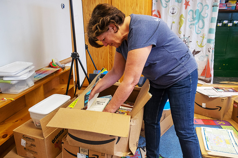 Teacher unpacking boxes in a classroom.