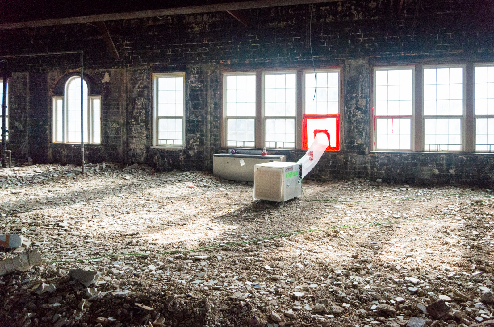 The third floor has been completely stripped with concrete and drywall rubble covering the floor.
