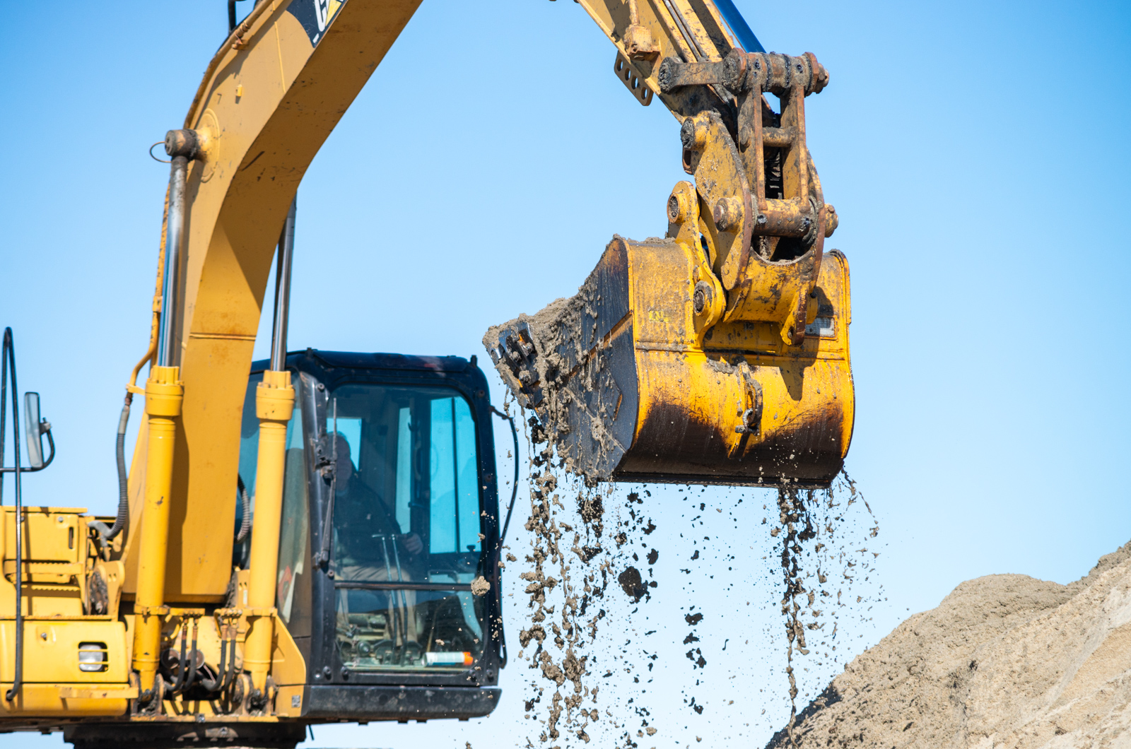Excavator digs up sand from dredge.