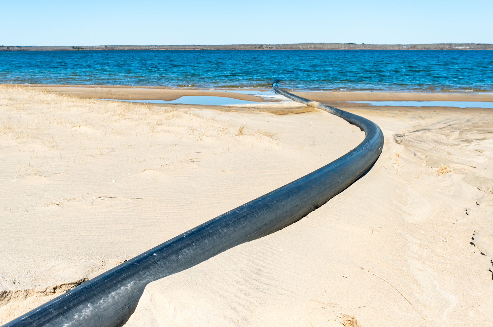 Dredge pipe stretching across the barrier beach.