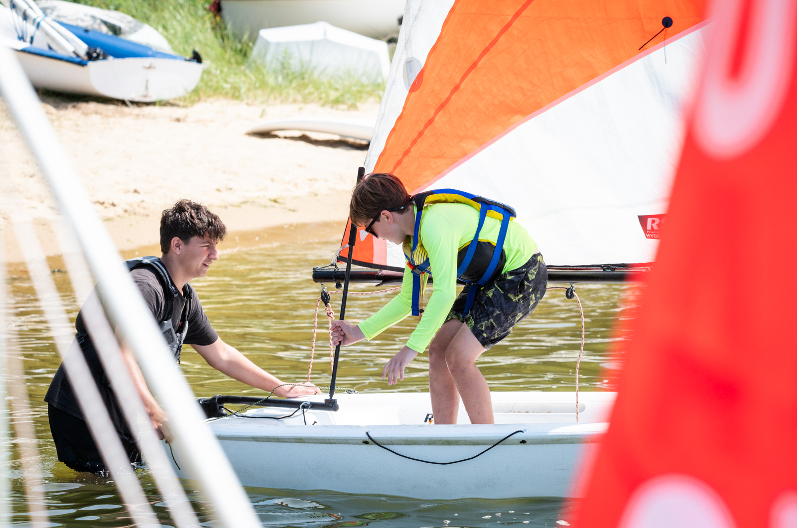 A Sail MV staff member helps a student get his boat ready.