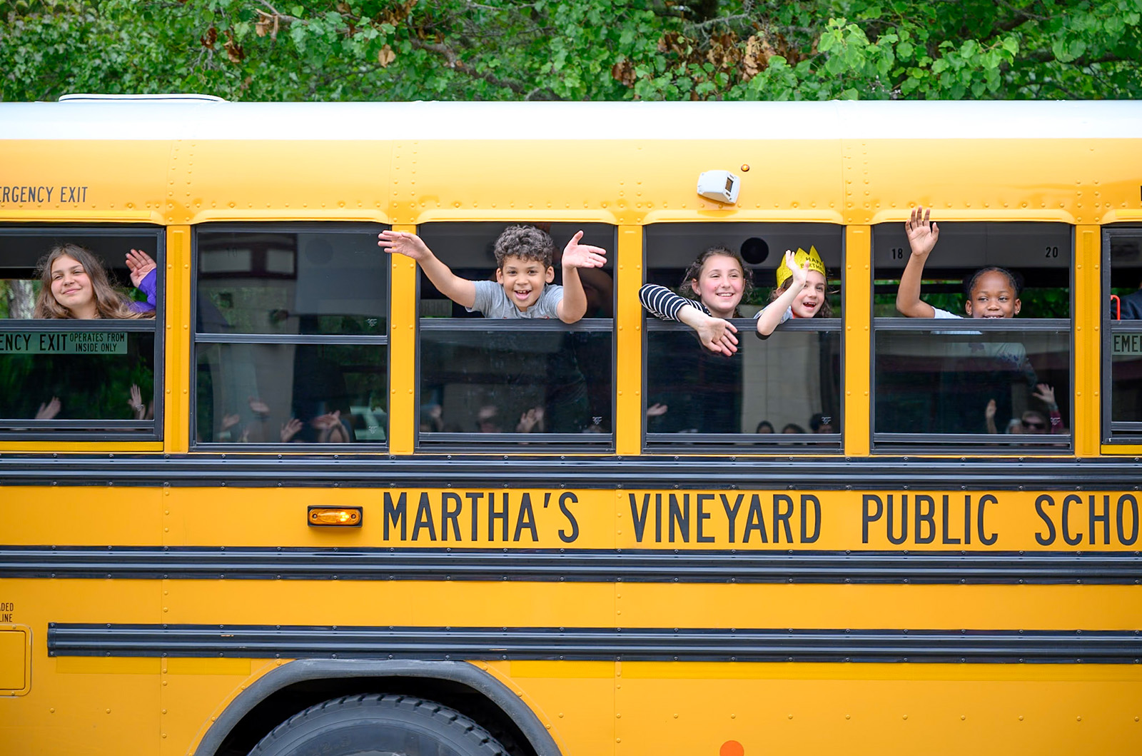 Students wave goodbye from the bus.