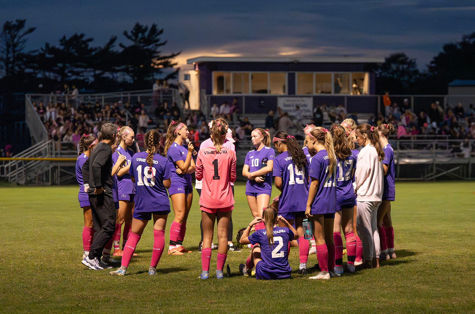 The Vineyard girls varsity team huddle sup with coach Matt Malowski.
