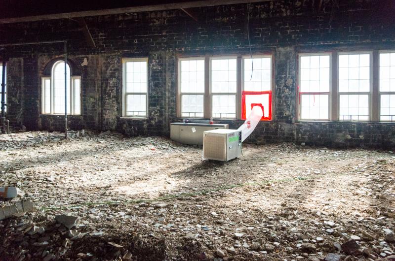 The third floor has been completely stripped with concrete and drywall rubble covering the floor.