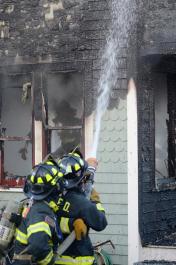 burning house firemen hose