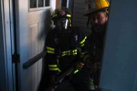 Firemen prepare entry into smoke filled building.