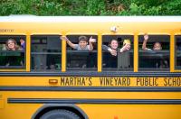 Students wave goodbye from the bus.